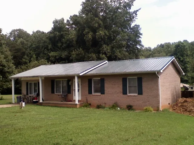 Gray metal roof on a brick ranch house with a side carport in Richmond